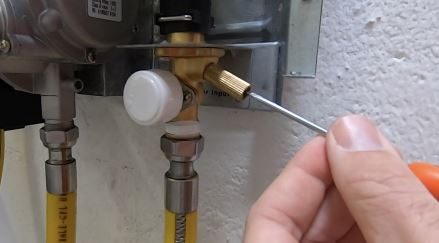 Screwdriver turning the OPV grub screw back so the valve starts to drip
