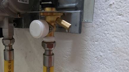 Over pressurisation valve on a gas geyser, with the brass grub screw to the right of the white valve cap