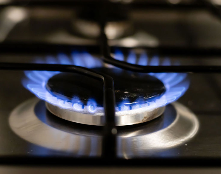 Gas hob burner lit with an even blue flame under a black pan support